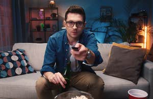 man sitting on couch holding remote watching TV