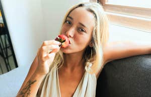 Gen-Z woman eating a strawberry.