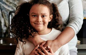 Child raised well, embraced by her mother's arms.