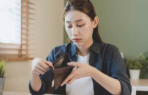 stressed woman looking at her empty wallet after paying fees