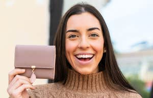 frugal woman holding up wallet smiling