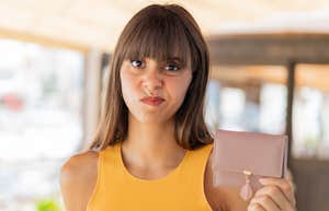 frugal woman holding purse after being raised by broke parents