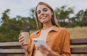 Reasons People Who Keep Their Phone On Silent 24/7 Usually Have smiling happy woman on her phone drinking coffee