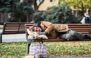 homeless man sleeping on a public bench outside