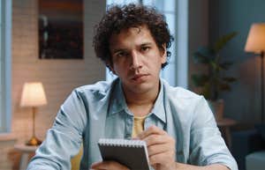 man with a notepad looking judgmental
