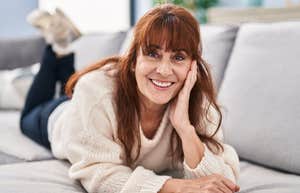 older woman smiling relaxing at home laying on the couch