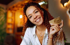 happy frugal woman holding credit card smiling