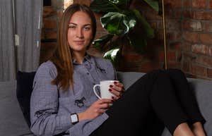 woman sitting on couch in leggings drinking coffee