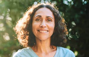 A calm, confident woman over fifty smiling gently outdoors, reflecting self-assurance, presence, and the kind of quiet confidence that earns lasting respect.