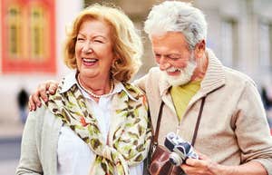 Smart Reasons To Spend Your Kids’ Inheritance While You’re Still Alive A happy mature couple smiling while traveling together, illustrating the 'giving while living' philosophy and the benefits of enjoying retirement wealth through shared adventures.