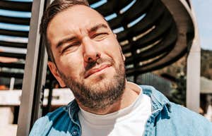 I Took The ‘Struggling Millennial’ Test And Signs Hit A Little Too Close To Home A handsome millennial man with a perplexed, squinting expression, illustrating the common emotional fatigue and uncertainty associated with the modern 'struggling millennial' experience.