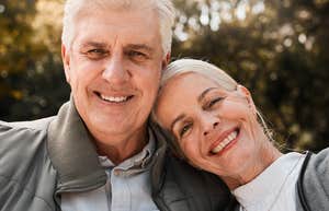 A mature newlywed couple in their 60s smiling warmly as the woman leans on her husband's shoulder, illustrating the unique trade-offs and emotional depth of finding love later in life.