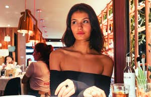 A woman sitting at a cafe table with a calm, discerning expression; illustrating the objective perspective single individuals have when identifying the patterns that newly married couples might overlook.
