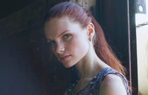 sad young woman by a window in a dark room who didn't get enough attention from parents as a child