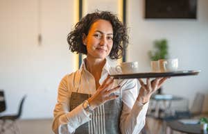 female server carrying tray with mugs