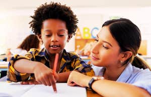 A teacher leaning in to help a student, capturing the 'emotional coaching' and the simple phrases that improve student behavior without raising a voice.