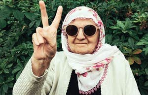 A stylish mature woman gesturing a peace sign with a beaming smile; illustrating the vibrant spirit and fashionable confidence that women in their sixties swear by to embrace their age.