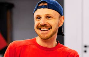A man smiling intently at the camera in a vibrant red shirt; illustrating the 'appeasement' behavior that can signal a lack of internal boundaries and reliability in a professional or personal setting.