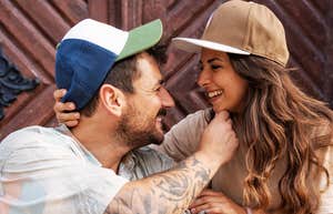A close-up outdoor lifestyle portrait of a happy young man and woman sitting close together, sharing an authentic laugh; illustrating 'the proximity-validation matrix' where mutual humor and shared spaces catalyze romantic pairings.