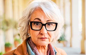 A classic portrait of a strong, mature female relative looking forward with a serious, discerning gaze; illustrating the defense of maternal choice and the confrontation of parental double standards within modern families.