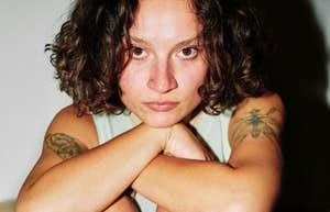 A close-up portrait of a woman with a neutral face resting on her arms; illustrating 'evolutionary signaling theory' and the non-obvious physical or behavioral traits that biological anthropologists say trigger instant social evaluations.