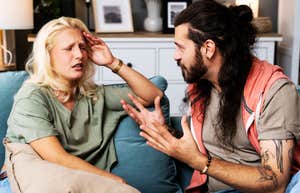 People With Zero Self-Awareness Almost Always Do Wildly Irrational Things When Arguing With You A close-up lifestyle shot of a young couple or roommates sitting in a tense posture in a home flat; illustrating 'the cognitive dissonance standoff' where a lack of internal insight leads to external blame-shifting during a dispute.