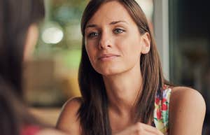 woman with slightly snide look on her face doesn't care about her friend who is talking 