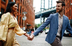 happy couple holding hands walking in city