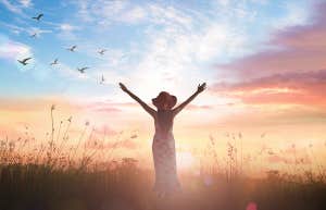 girl in sunset with arms raised
