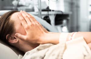 woman lying in hospital bed with hands over face