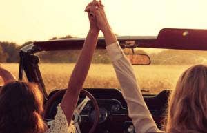 two women holding hands on road trip