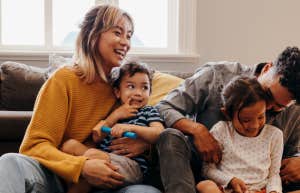 Young family of mixed race cuddles children in the living room