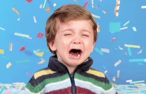 Little boy crying in front of falling birthday confetti