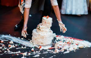 person picking up smashed wedding cake from the floor
