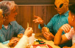 extraterrestrial being having a meal with a family like it's no big deal