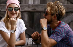 Couple sitting at a picnic table, him looking at her, she is smiling