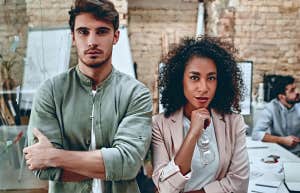 Two employees in their thirties in the workplace, looking like they are in conflict