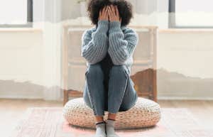 Unhappy woman sitting on pouf in living room