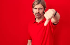 man in his 40s standing in front of red background