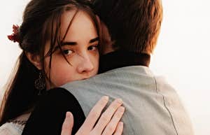 woman looking serious, peering over the shoulder of a man