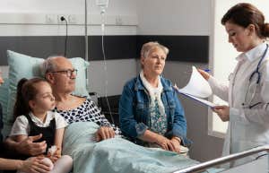 family sitting around man in hospital bed