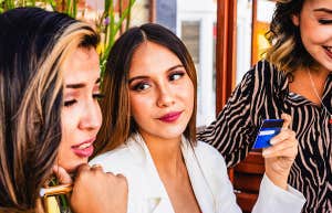 group of girl friends, one holding credit card up