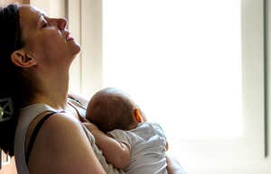 woman holding baby with back against wall