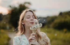 woman blowing a dandelion