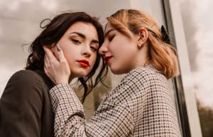 two women embracing, a brunette looking at the camera