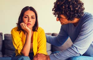 man and woman sitting on the couch, he is trying to get her to talk to him