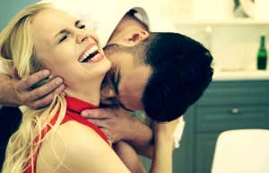 a seated woman laughs in pleasure as a man kisses her neck from behind her