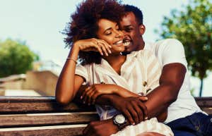 happy couple sitting on a bench hugging