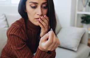 sad woman holding husband ring