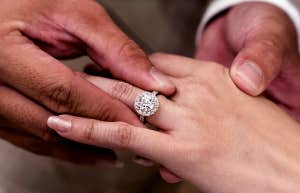 man putting engagement ring on woman's finger